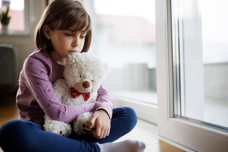 A young child holding a teddy bear, reflecting hidden depression during a therapy session